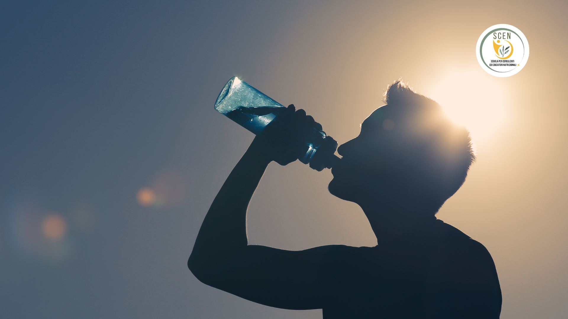 un uomo sotto al sole in penombra che beve l'acqua per idratarsi