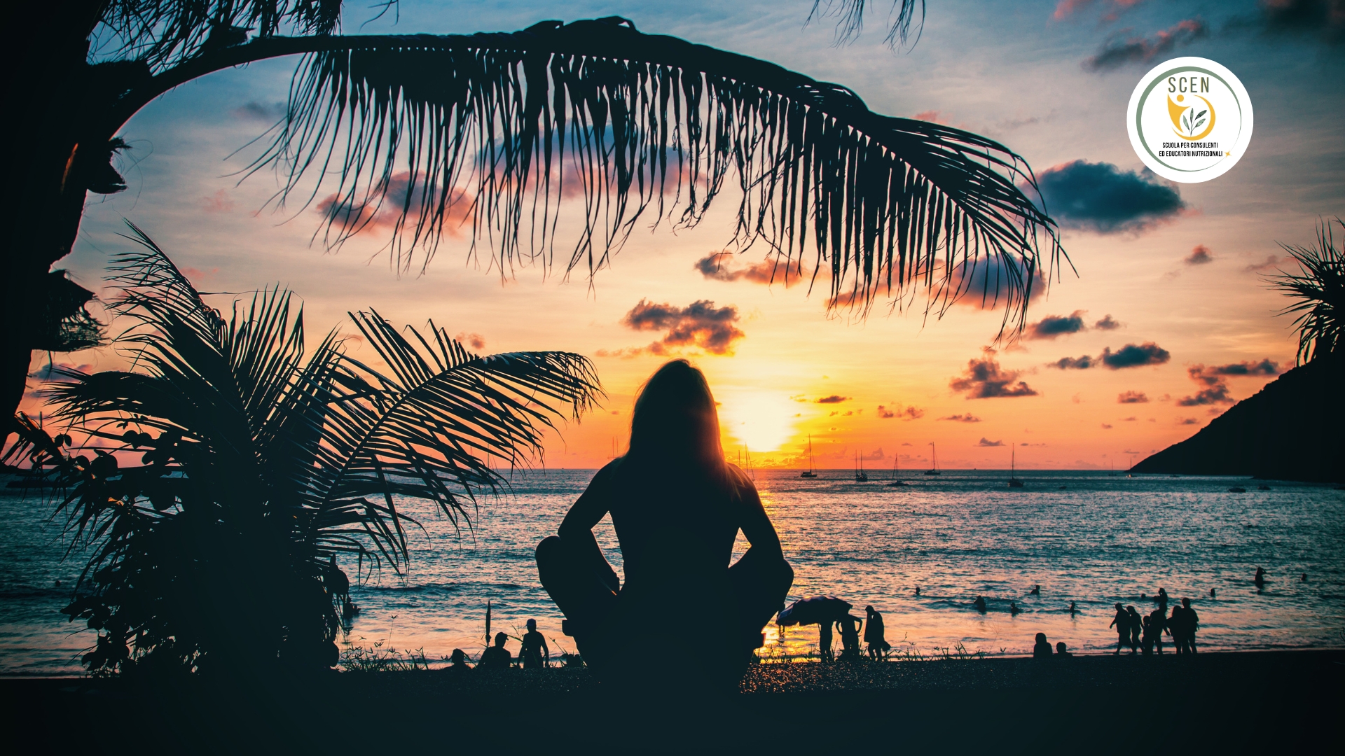 ragazza seduta di spalle su una spiaggia davanti ad un tramonto di settembre